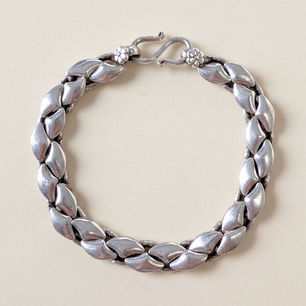 Silver bracelet with leaf-like design on a white background