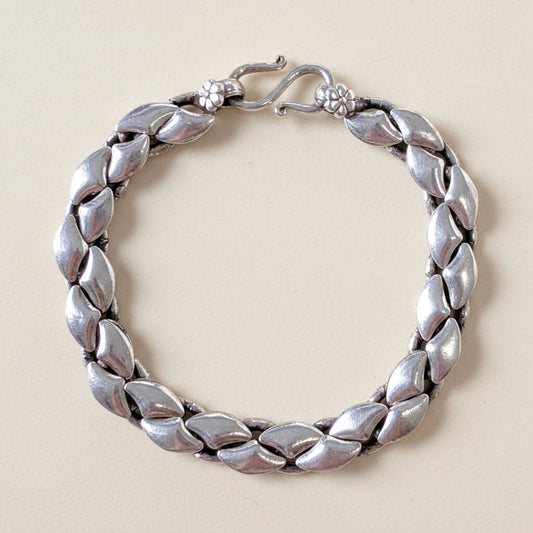 Silver bracelet with leaf-like design on a white background