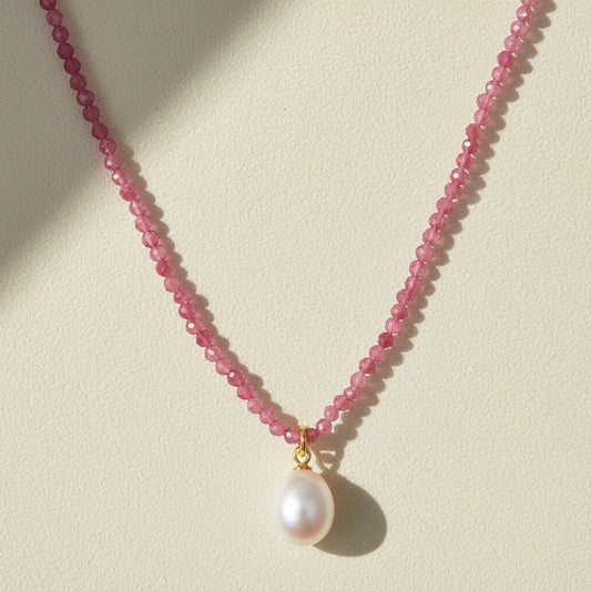 Pink beaded choker necklace with a round white pearl pendant on a gold bail