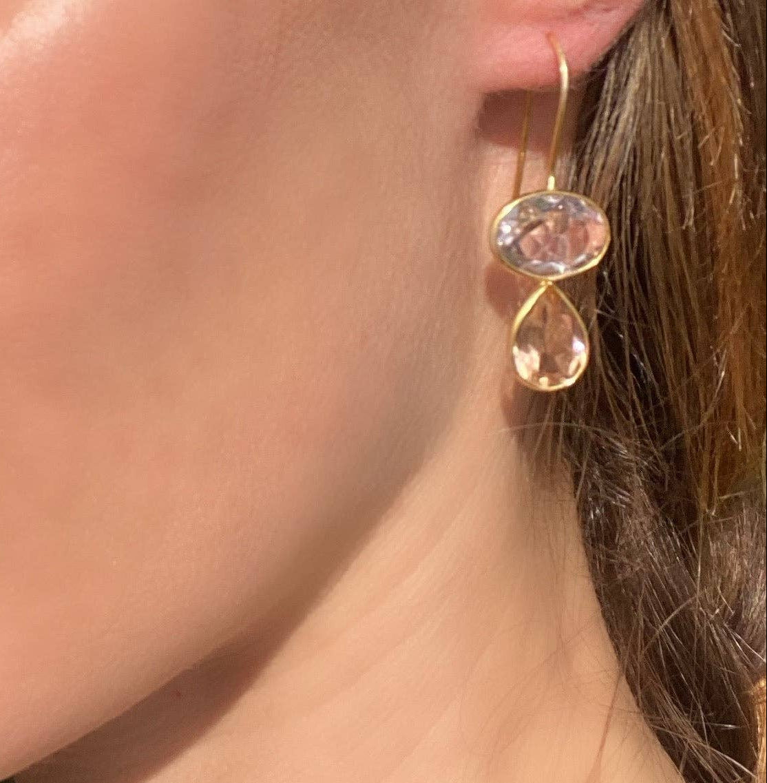 Teardrop drop earrings on ear with gold hooks and pink faceted stones