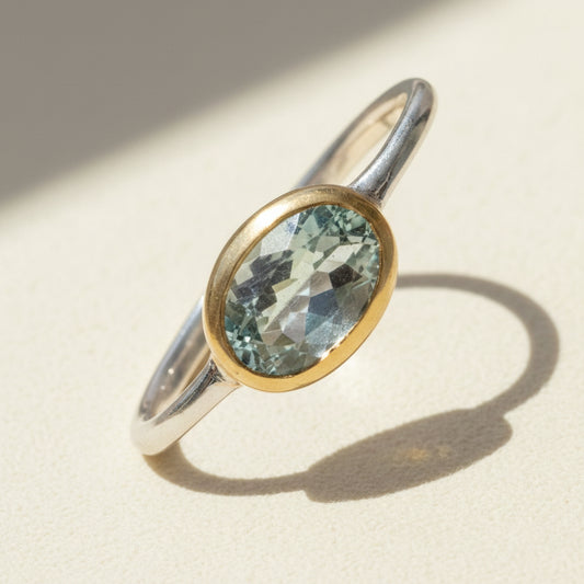 Two-tone aquamarine ring with oval blue-green stone and gold bezel