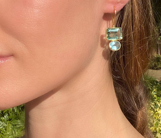 Gold drop earrings on ear with square aqua and round lime green gemstones