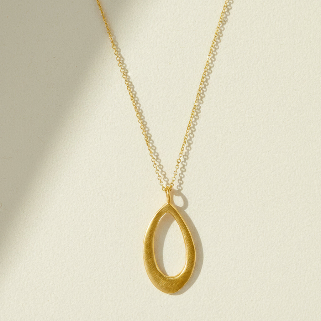 Gold leaf-shaped pendant necklace with slim chain and open teardrop charm