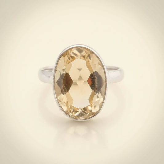 Ring with a large faceted yellow gemstone on a white background