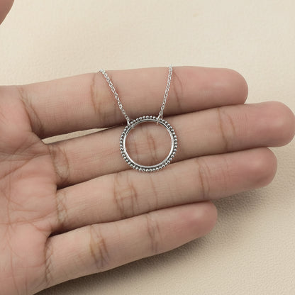Silver circle pendant necklace with dotted edge, worn on hand, link chain