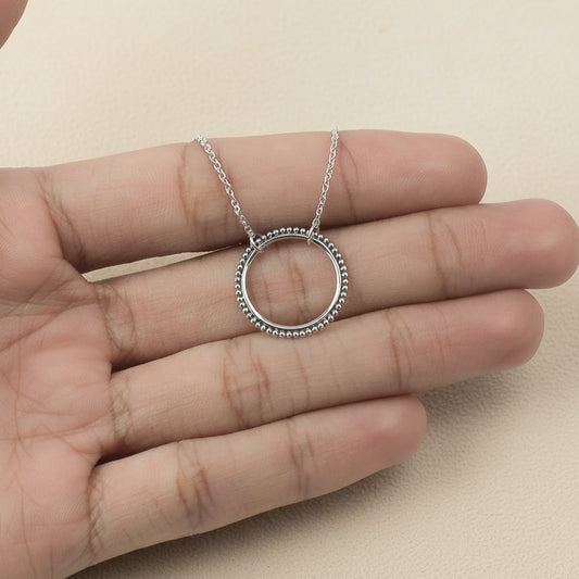 Silver circle pendant necklace with dotted edge, worn on hand, link chain