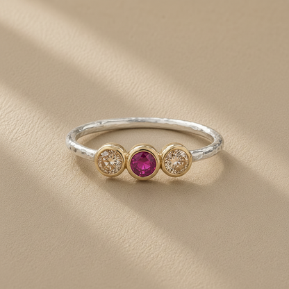 Silver ring with three gemstones on a beige background