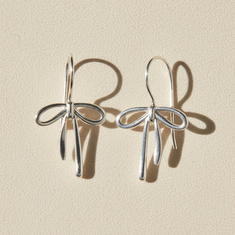 Silver bow tie ribbon drop earrings with dangling charms