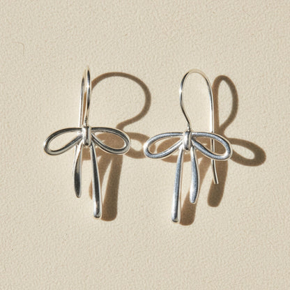 Silver bow tie ribbon drop earrings with dangling charms