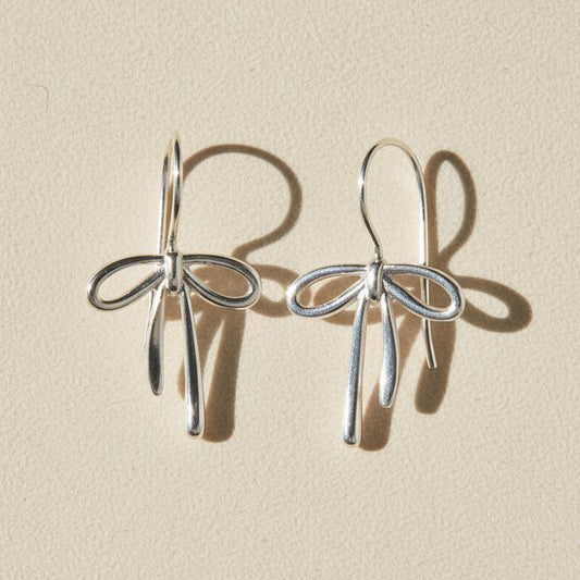 Silver bow tie ribbon drop earrings with dangling charms