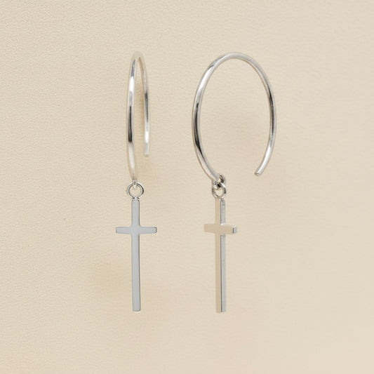 Silver hoop earrings with small cross charms dangling from hinged loops