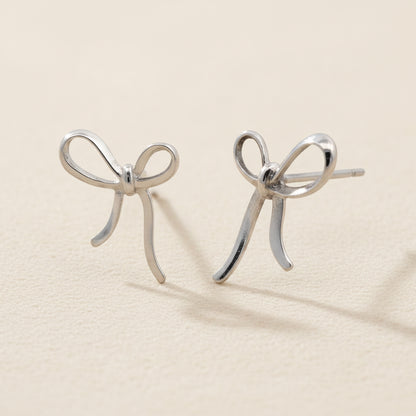 Small ribbon bow stud earrings in silver-tone metal with curved loops and tails