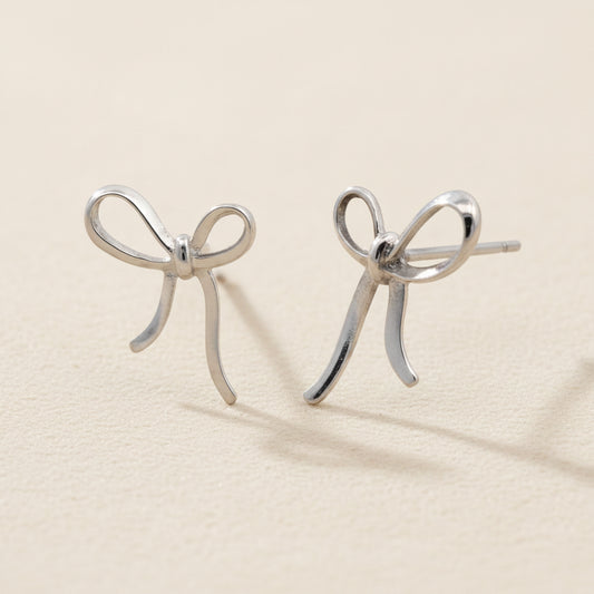 Small ribbon bow stud earrings in silver-tone metal with curved loops and tails