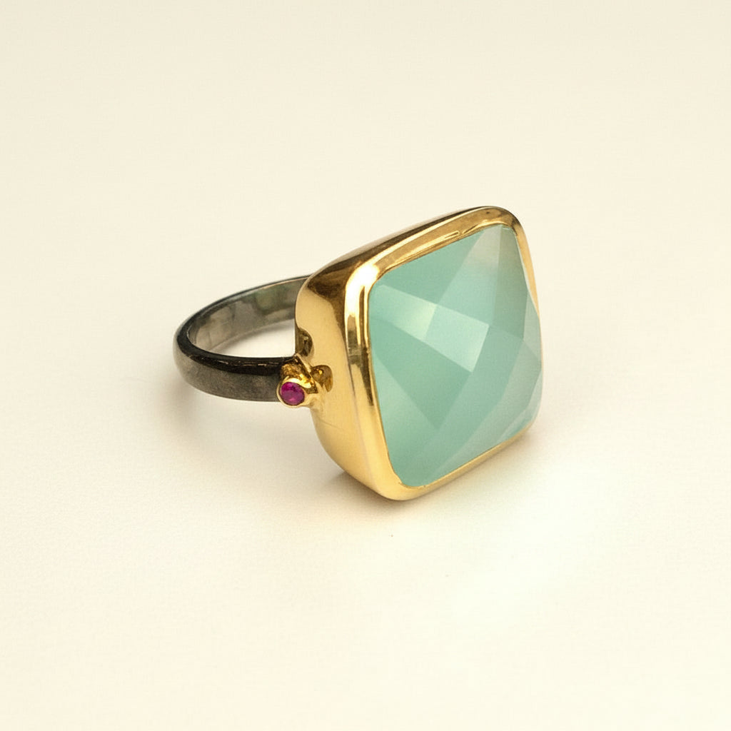Ring with a gold band and green gemstone on a white background