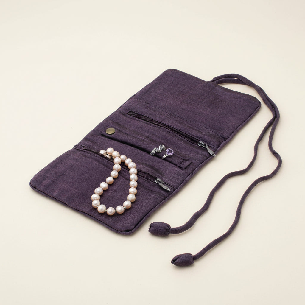 Purple jewelry roll with pocket panels and drawstring ties, holds pearl-like beads
