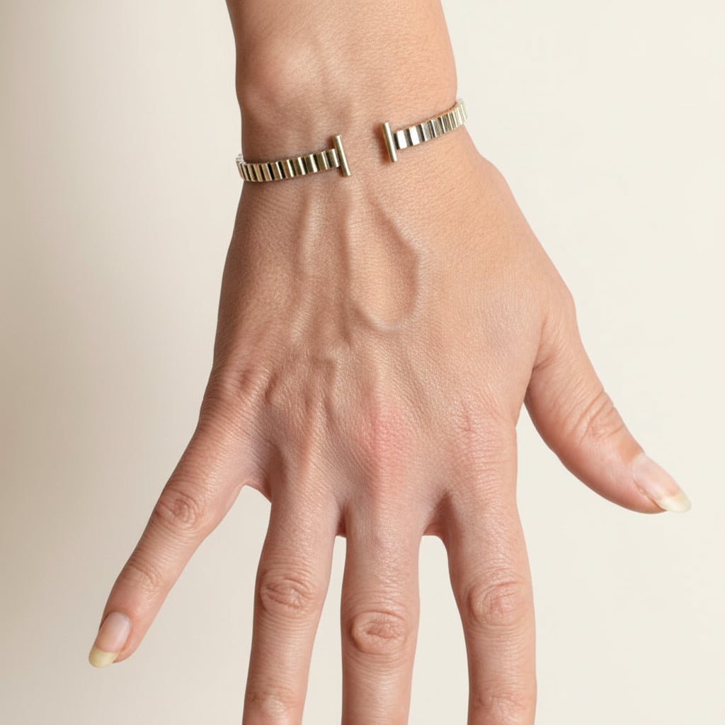 Striped silver cuff bracelet worn on wrist, with hinge bar closure and ridged band