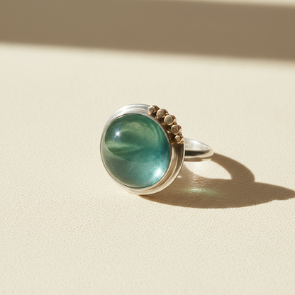 Silver ring with large round green cabochon, side view with gold-tone stud setting
