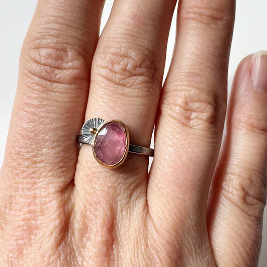 Minimal oval pink sapphire ring on hand, silver band with bezel and small prong details