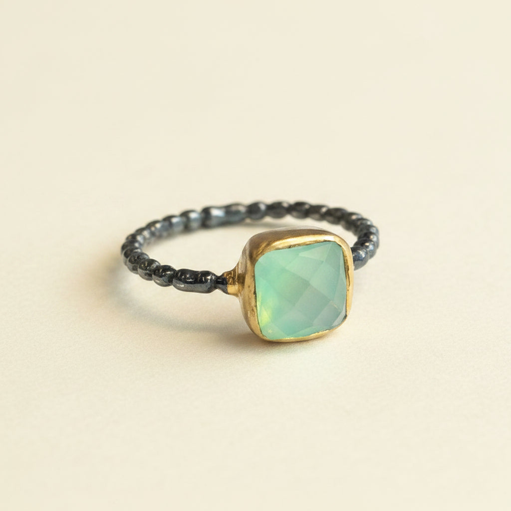 Ring with a green gemstone and gold accents on a white background