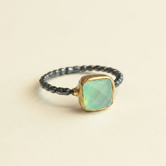 Ring with a green gemstone and gold accents on a white background
