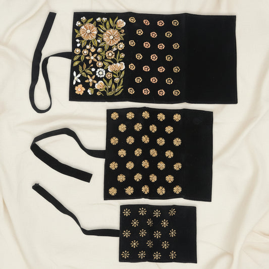Black beaded jewelry roll with gold floral bead patterns and three storage panels
