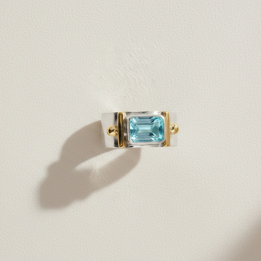 Wide band gemstone ring with rectangular sky-blue topaz and gold-tone bezels