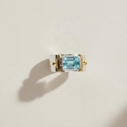 Wide band gemstone ring with rectangular sky-blue topaz and gold-tone bezels