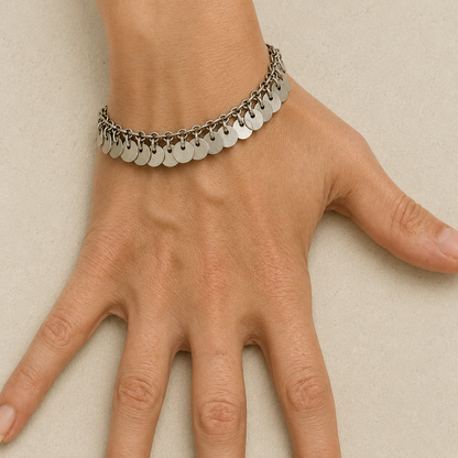 Silver chain bracelet with round disc dangles across the wrist