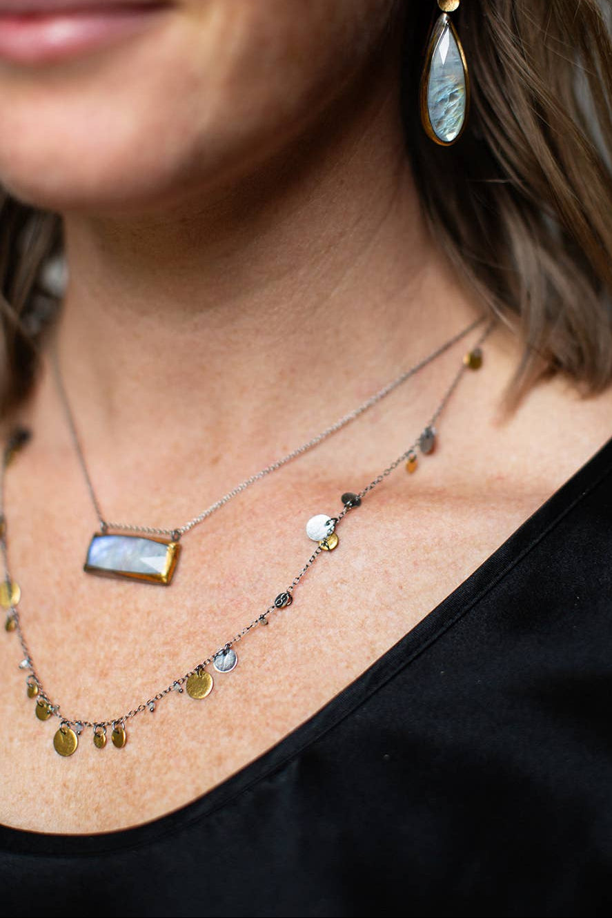 Charm necklace with mixed gold and silver coins, teardrops, and a blue pendant bar
