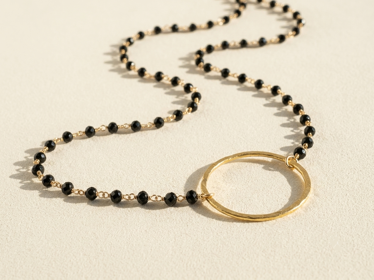 Black beaded necklace with gold ring pendant and small black faceted stones