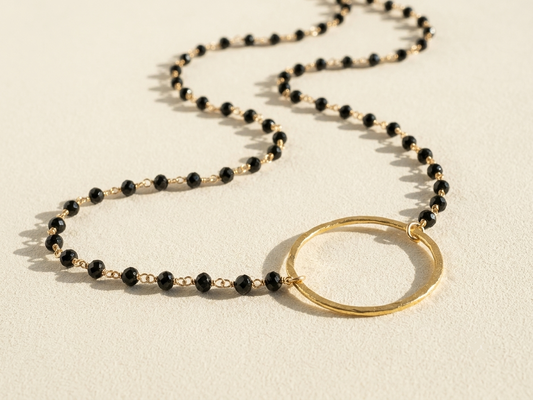 Black beaded necklace with gold ring pendant and small black faceted stones