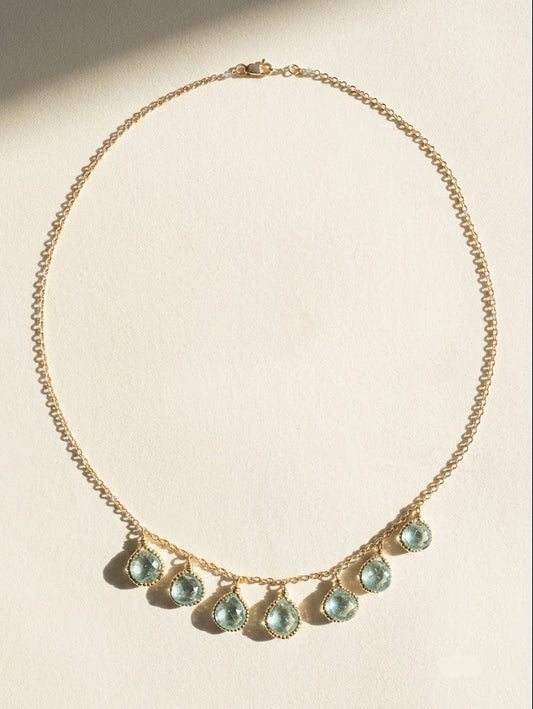 Gold-tone briolette necklace featuring small teal teardrop beads along the front