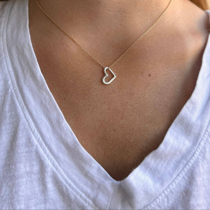 Gold-tone open heart pendant necklace resting on neckline