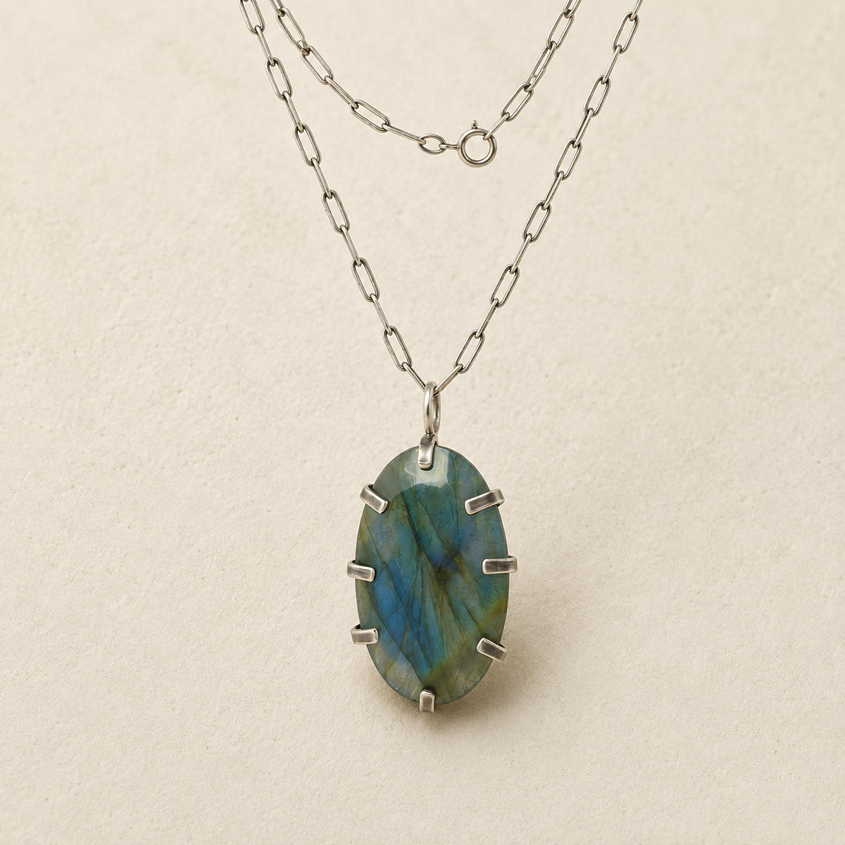 Oval labradorite pendant on silver-tone chain, faceted blue-green stone with metal prongs