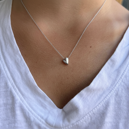 Heart pendant necklace with small silver heart charm, worn on collarbone