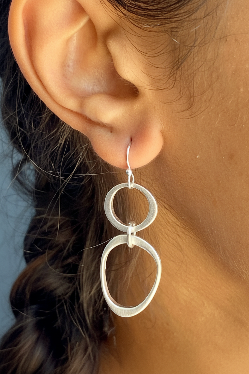 Silver double-circle drop earrings close-up on ear with hook back