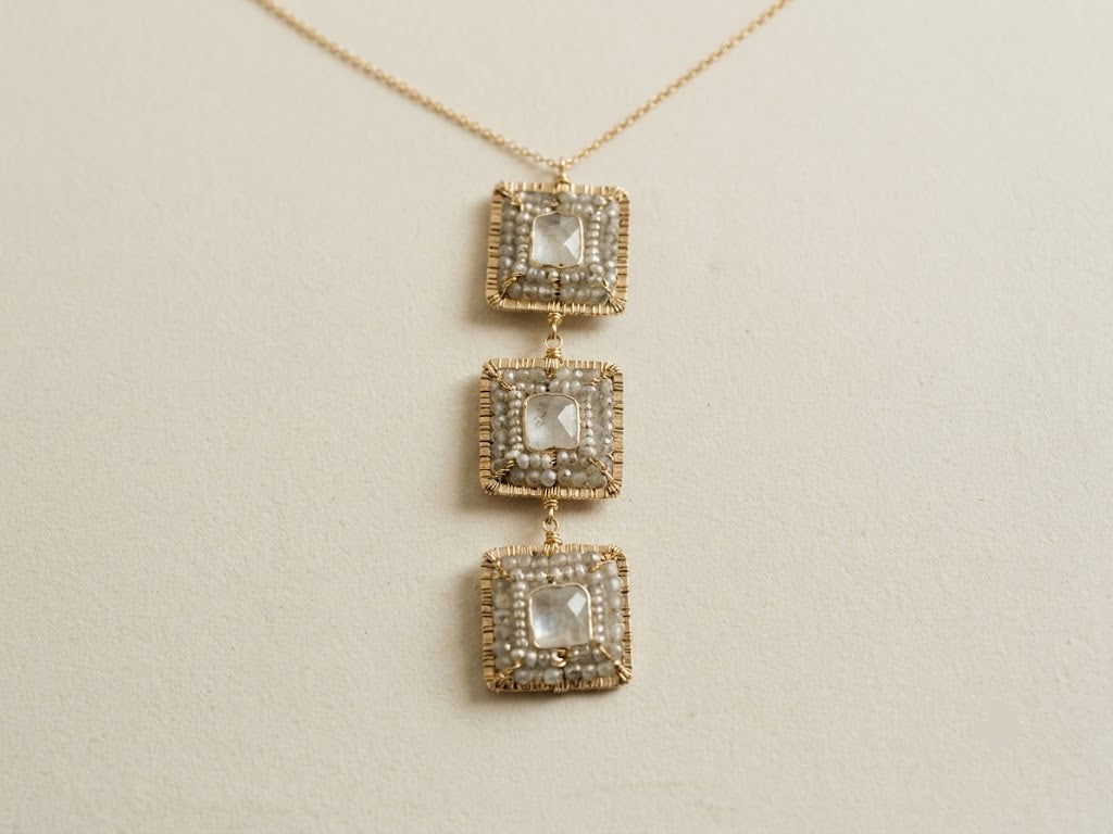 Gold-tone necklace pendant with three stacked square frames and pearl-like insets