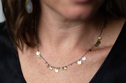 Gold-tone coin and teardrop charm necklace with sparkling discs on a chain