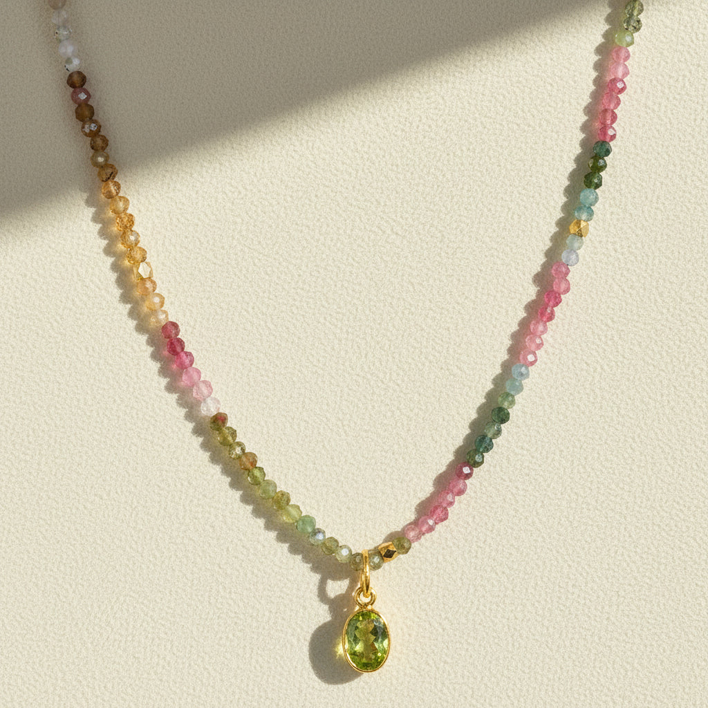 Multicolor beaded charm necklace with gold clasp and green teardrop pendant.