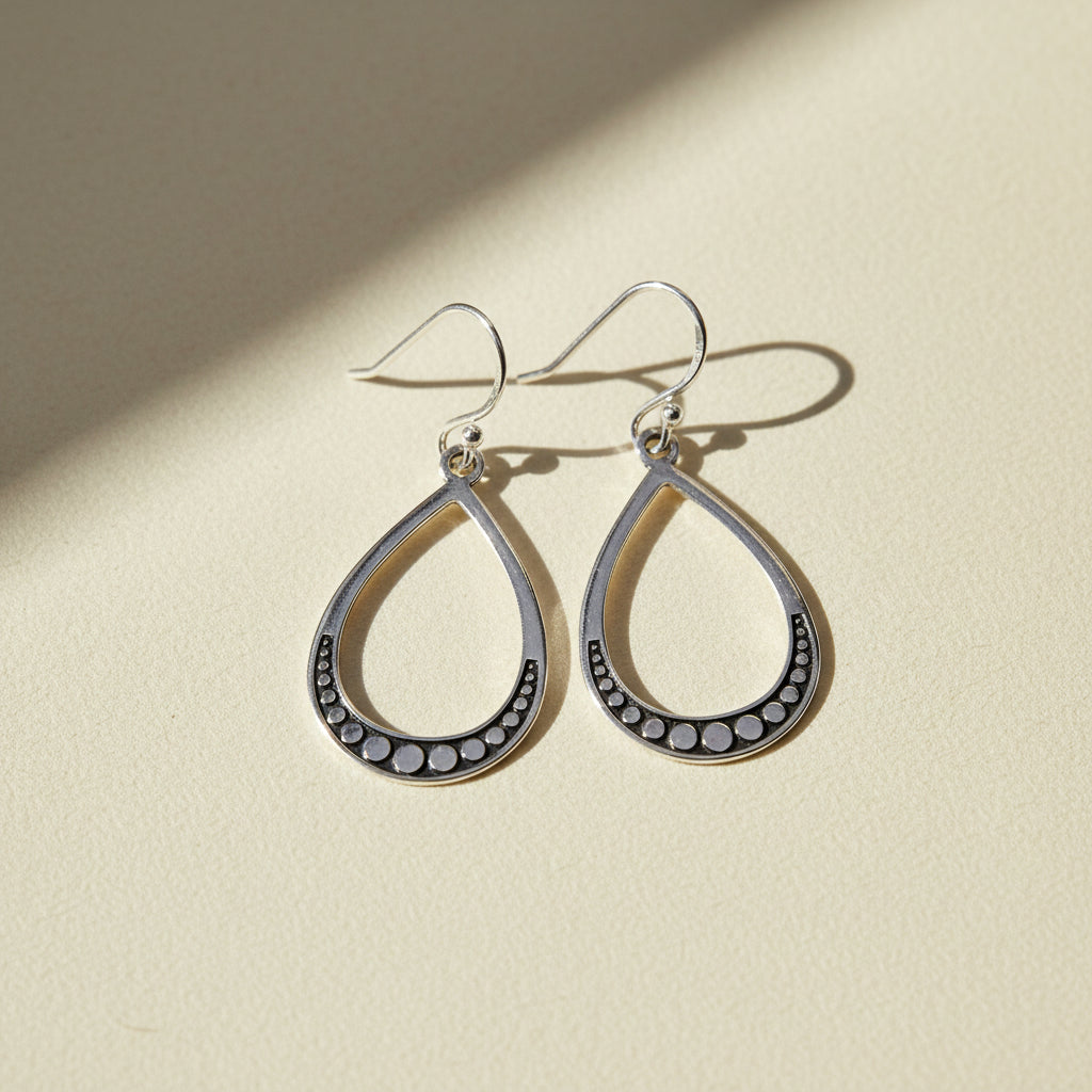 Large silver teardrop beaded earrings with dark bead border and hoop hooks