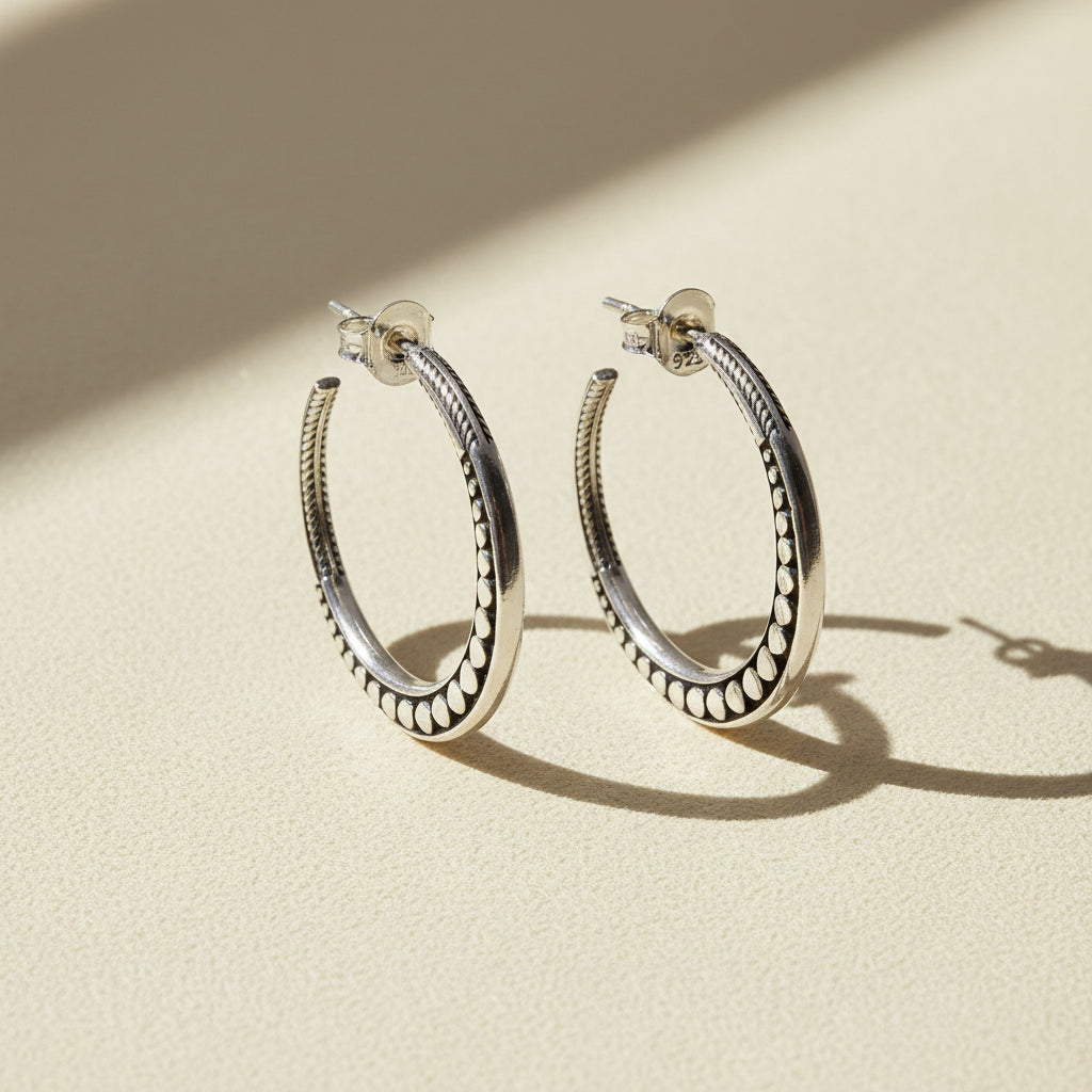 Silver-tone beaded hoop post earrings with textured edging and circular inner loop.