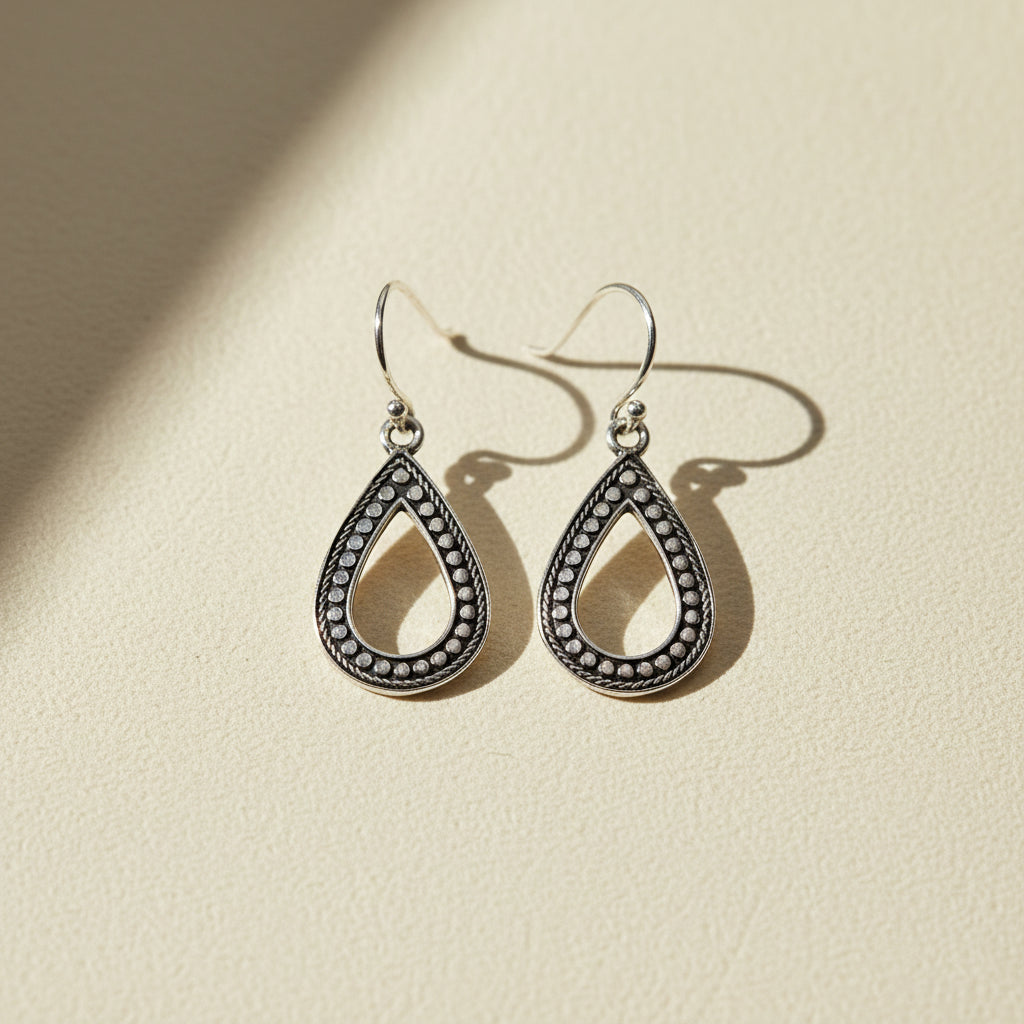 Silver-tone teardrop earrings with dark beaded trim and hook backs