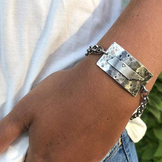 Silver-tone chain bracelet with rectangular city-themed charm and dangling accents