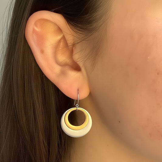 Two-tone circle drop earrings on ear, gold center with silver outer ring
