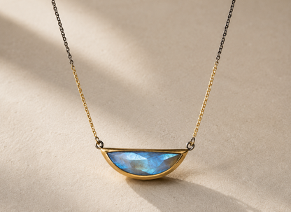 Gold-tone necklace with large crescent blue faceted gemstone pendant