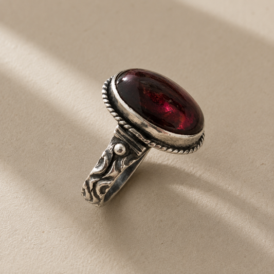 Garnet cabochon oval ring with ornate silver band and dark red oval stone