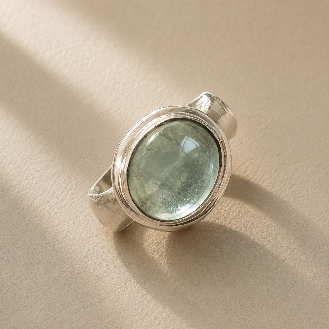 Sterling silver ring with oval bezel-set light green cabochon gemstone