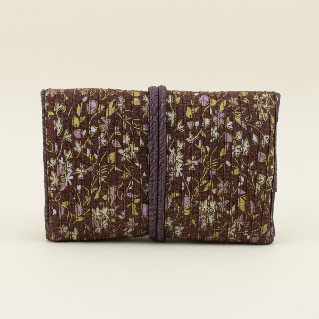 Floral fabric jewelry roll with dark tie strap, folded compartments