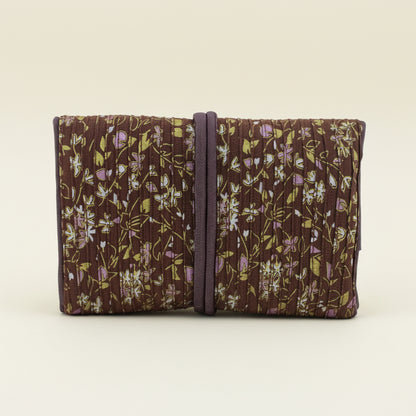 Floral fabric jewelry roll with dark tie strap, folded compartments