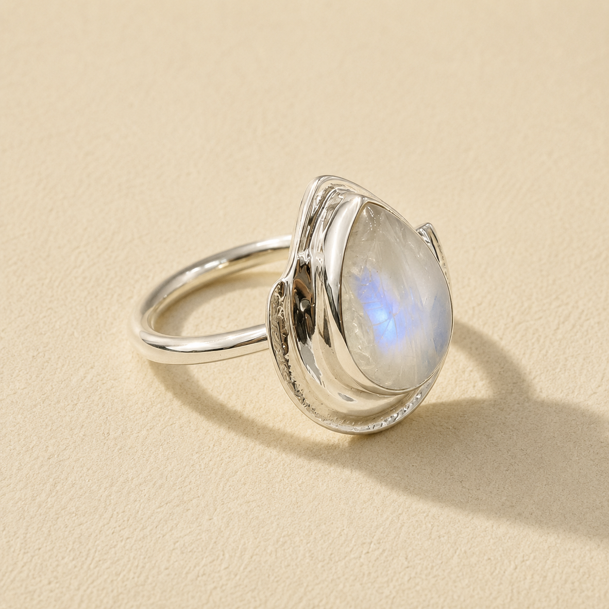 Silver teardrop moonstone ring with blue iridescent stone set in curved bezel